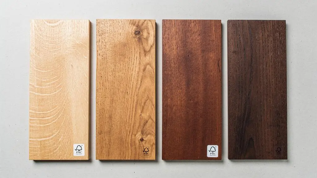 Échantillons de différentes essences de bois disposés côte à côte montrant leurs grains naturels et variations de couleurs, du chêne clair au noyer foncé.